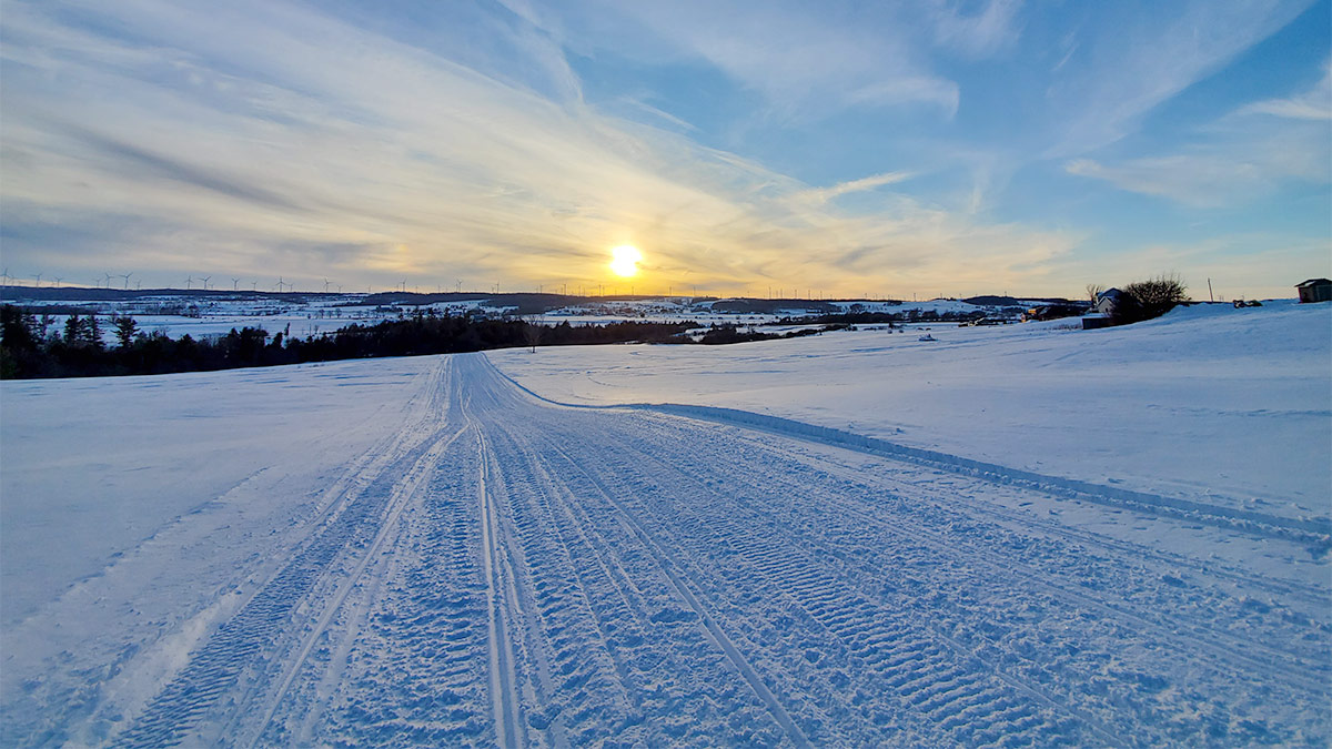 winter snowmobile trail heading into the sunset